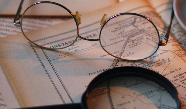 Lunettes rondes et loupe posées sur une carte ancienne.