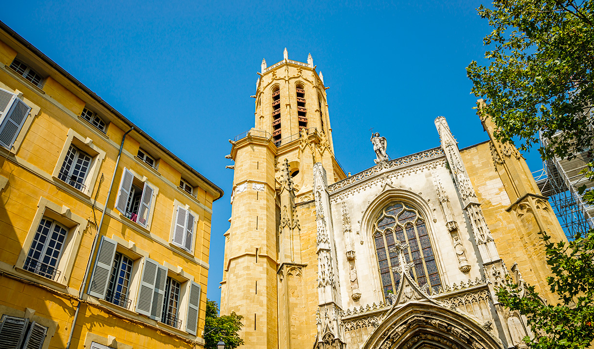 Façade gothique et tour de la cathédrale Saint-Sauveur à Aix-en-Provence sous un ciel bleu.