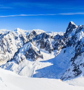 Paysage alpin enneigé sous un ciel bleu.