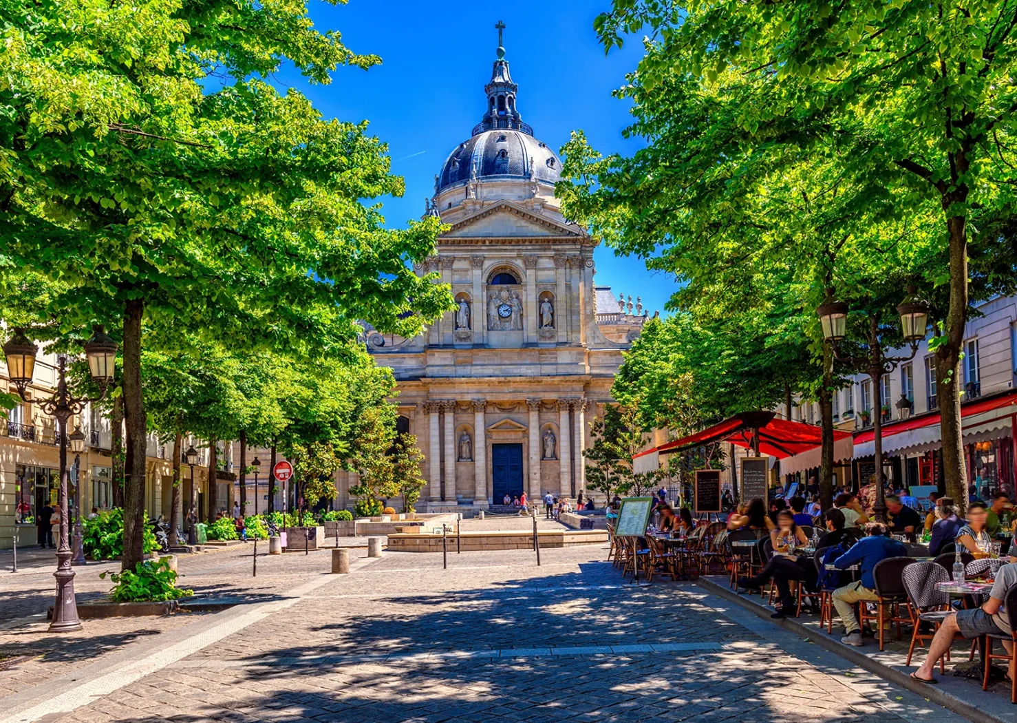 Place de la Sorbonne à Paris avec ses terrasses de café et la chapelle universitaire en arrière-plan.