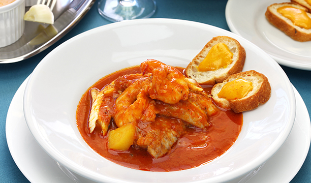 Assiette de bouillabaisse servie avec des tranches de pain et de la rouille.