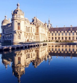 Château ancien se reflétant dans un lac par une journée ensoleillée.