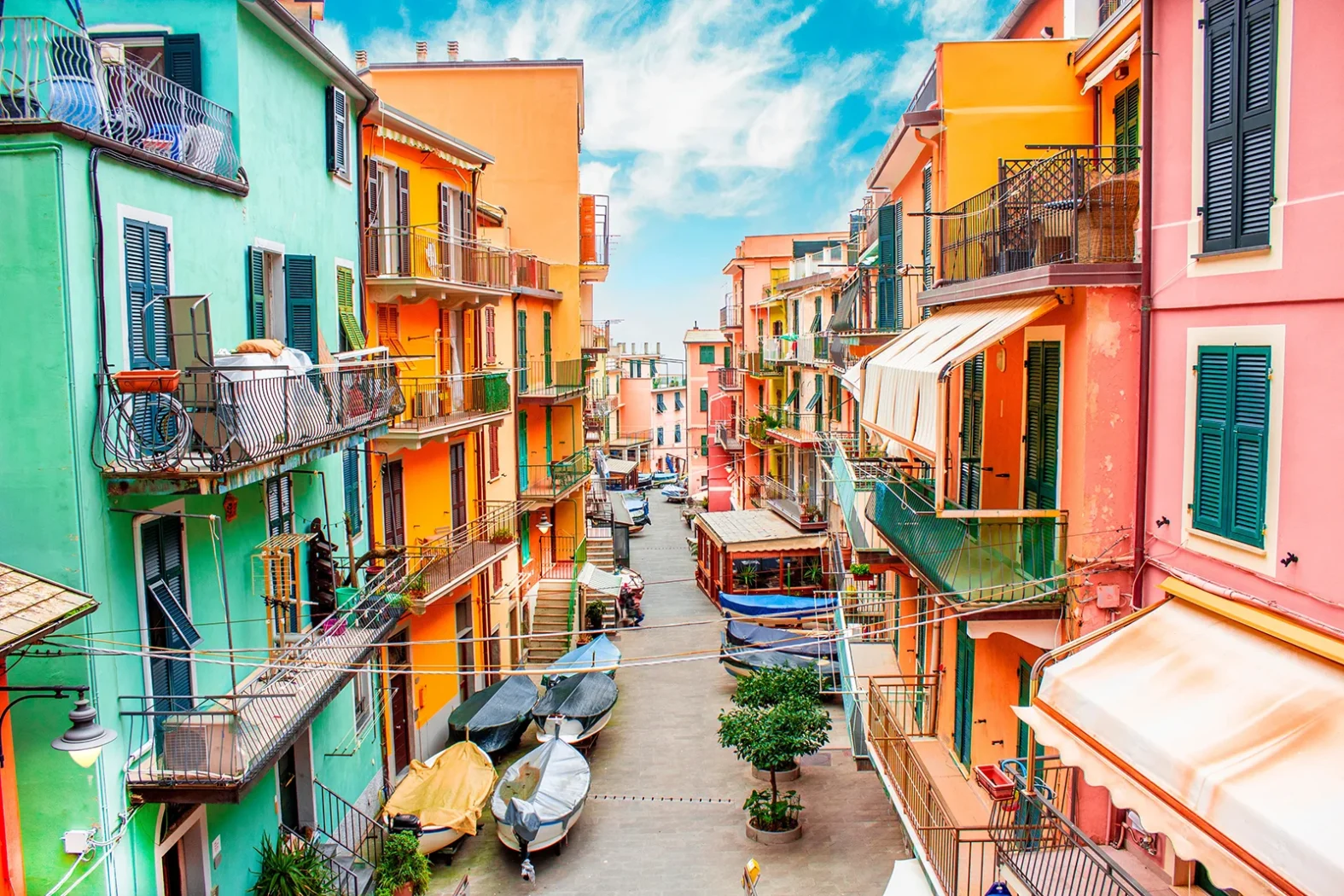 Rue étroite bordée de maisons aux façades multicolores à Manarola, avec des barques garées au sol.