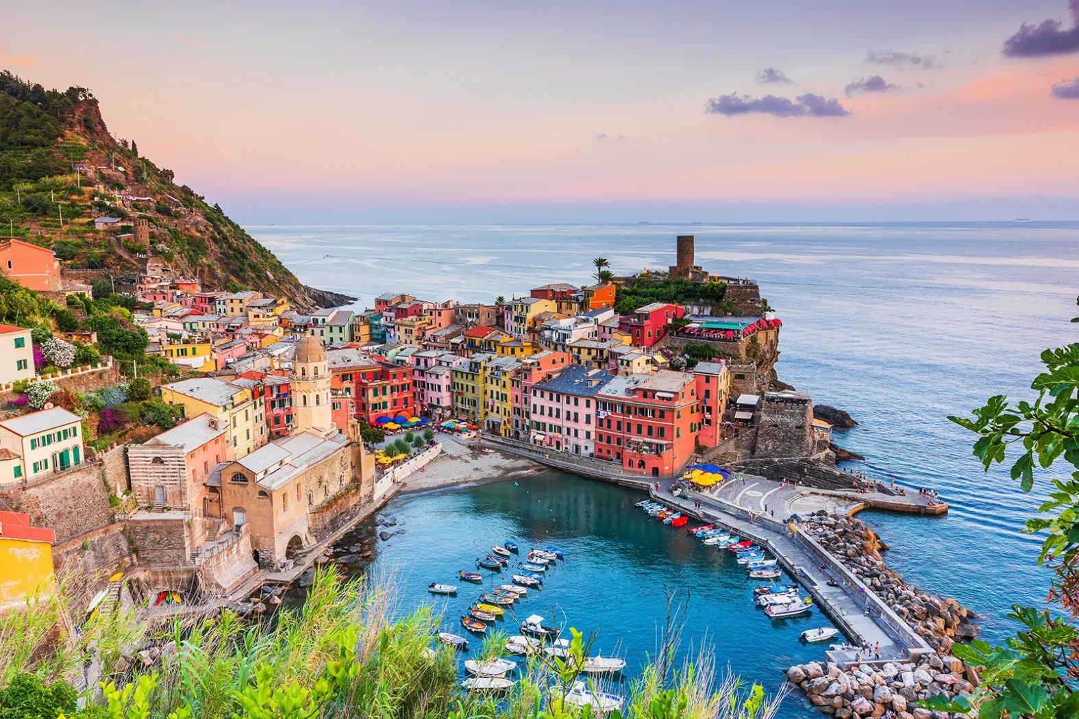 Vue aérienne sur le village de Vernazza au crépuscule, ses maisons colorées et son petit port donnant sur la mer Ligure.