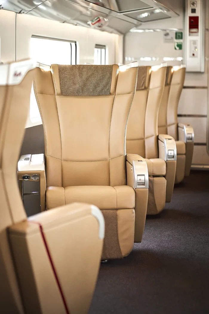 Sièges en cuir beige spacieux et confortables dans une voiture de première classe d’un train Frecciarossa Trenitalia