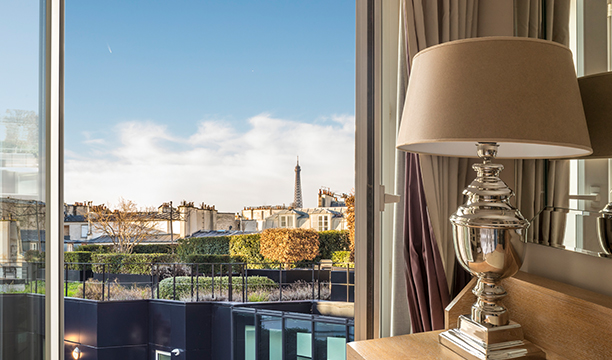 Vue depuis une chambre d’hôtel sur les toits de Paris avec la tour Eiffel au loin.