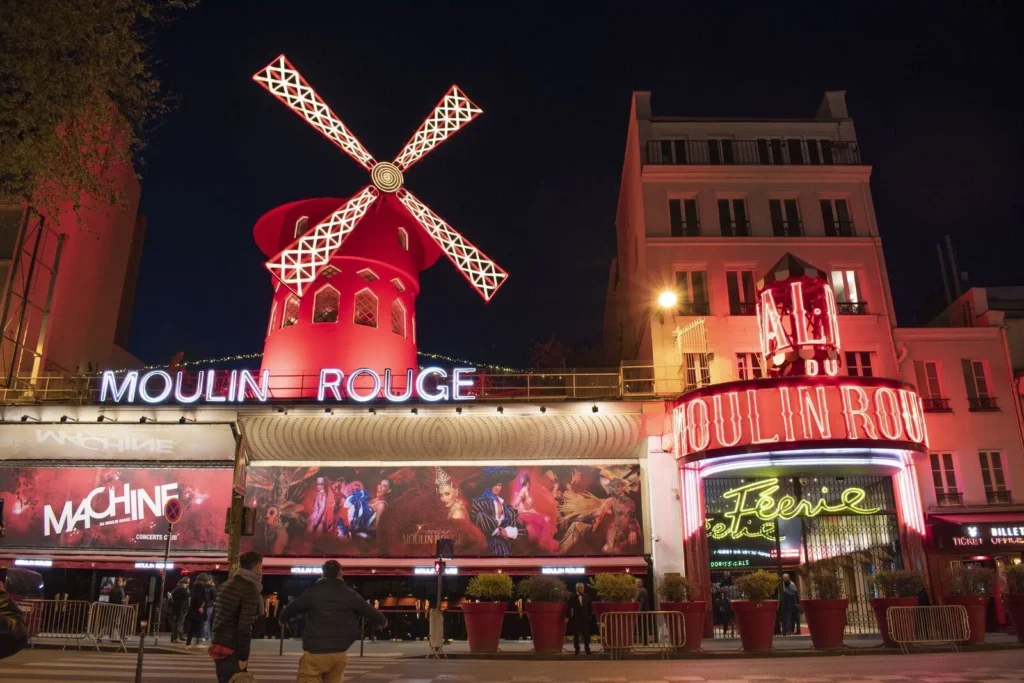 Façade illuminée du Moulin Rouge à Paris de nuit.