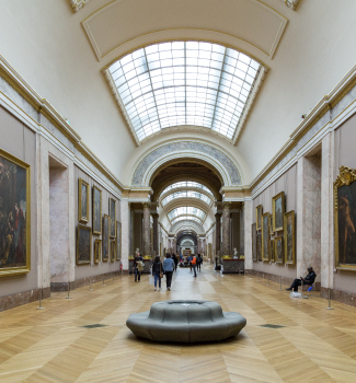 Galerie d’un musée avec des tableaux accrochés aux murs et des visiteurs qui se promènent.