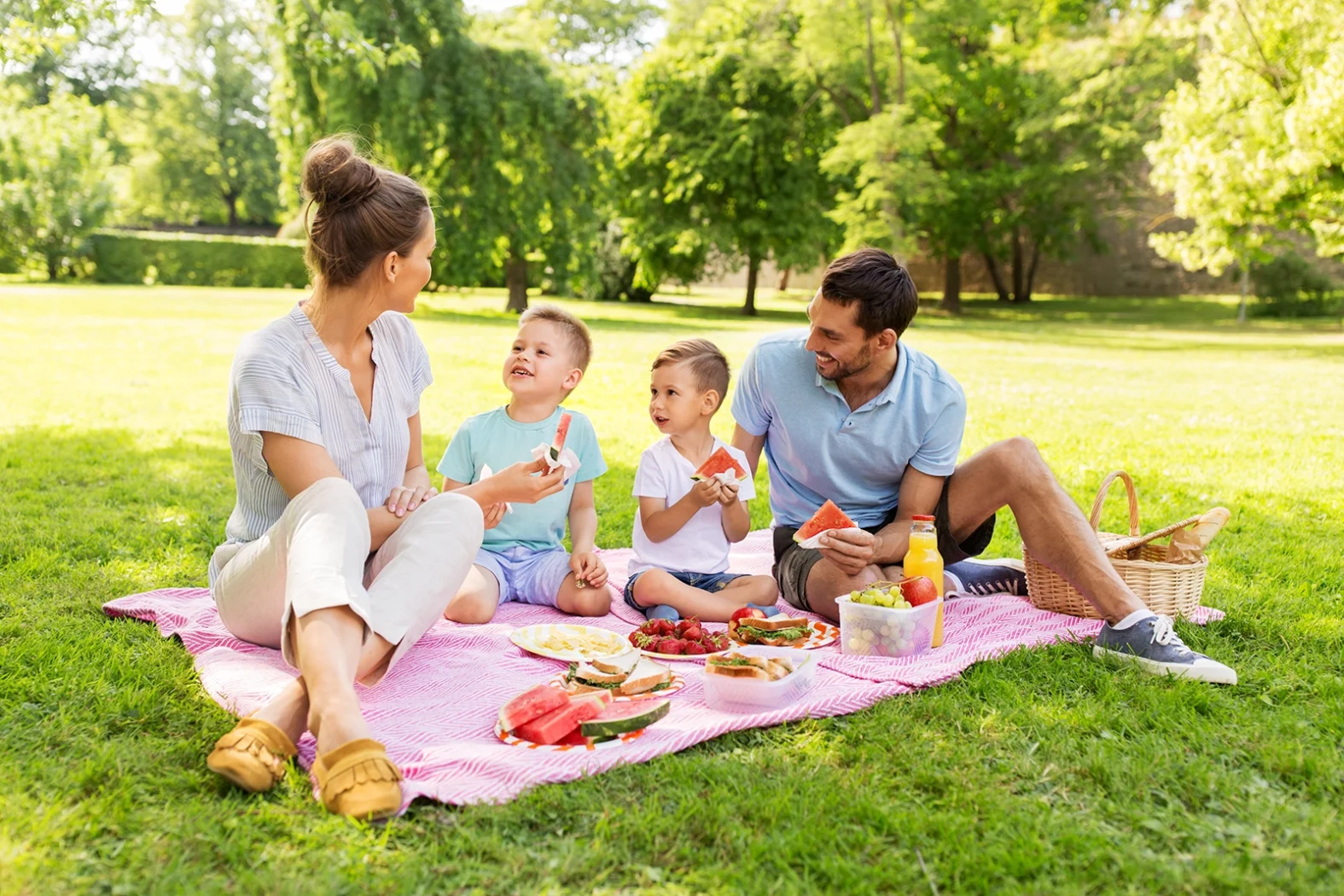 Famille faisant un pique-nique dans un parc ensoleillé.