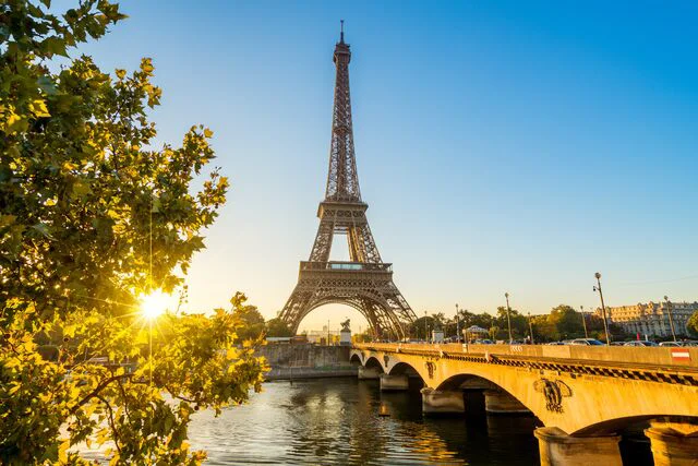 Tour Eiffel au coucher du soleil avec le pont d’Iéna et la Seine en premier plan.