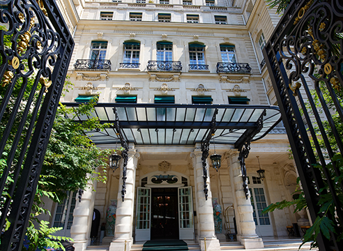 Entrée majestueuse d’un hôtel parisien avec une verrière et des grilles en fer forgé.