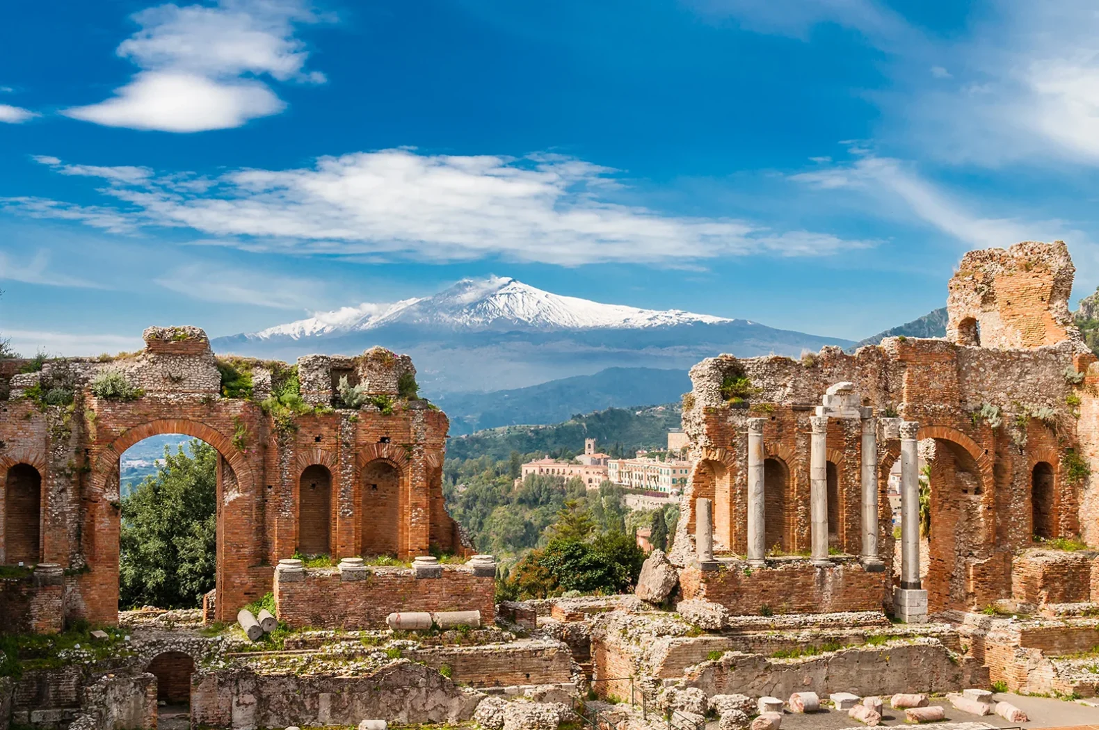 Ruines d’un ancien théâtre en Sicile avec le mont Etna enneigé en arrière-plan.