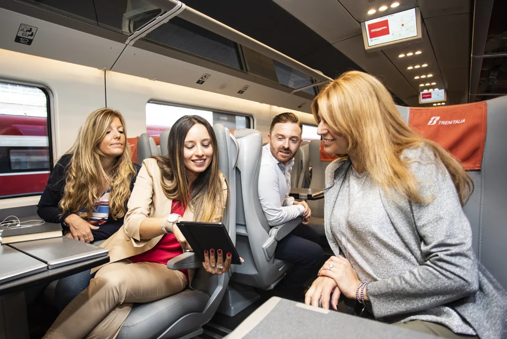 Groupe de voyageurs échangeant à bord d’un train Trenitalia