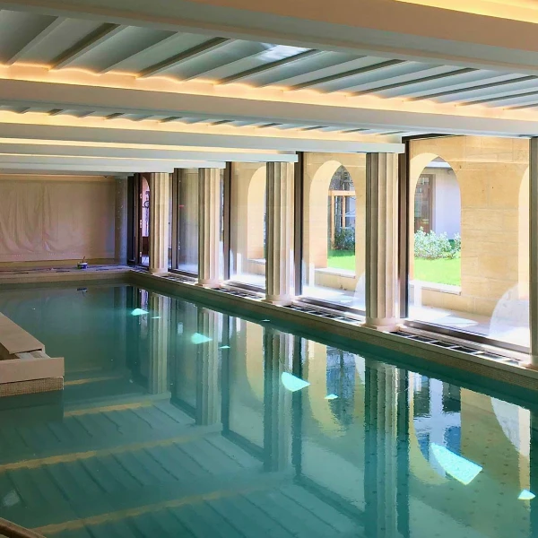 Piscine intérieure lumineuse avec grandes baies vitrées.
