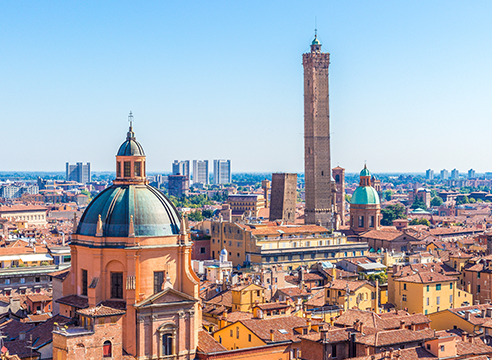 Vue panoramique sur la ville de Bologne avec ses tours médiévales et dômes colorés.