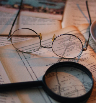 Lunettes rondes et loupe posées sur une carte ancienne.