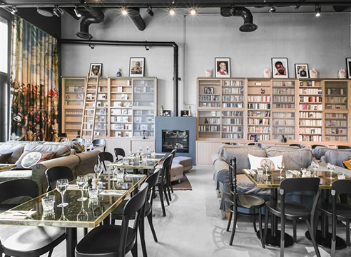 Intérieur d’un restaurant parisien moderne avec étagères de livres, tables dressées et ambiance cosy.