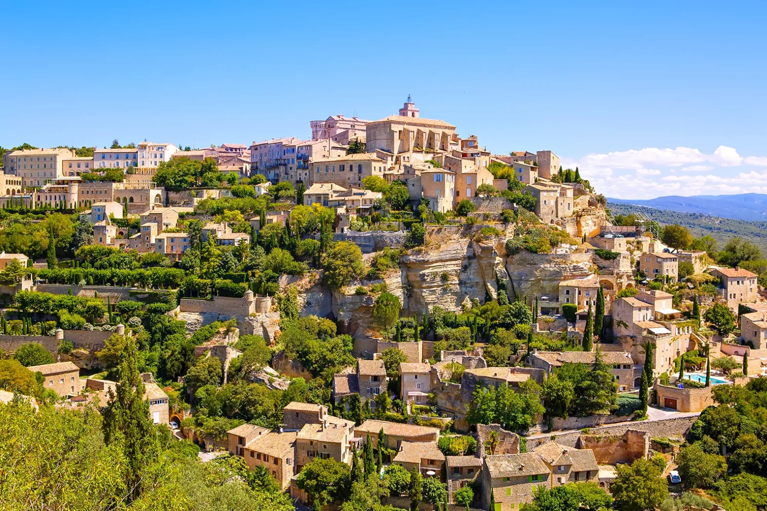 Vue panoramique du village perché de Gordes en Provence sous un ciel bleu.