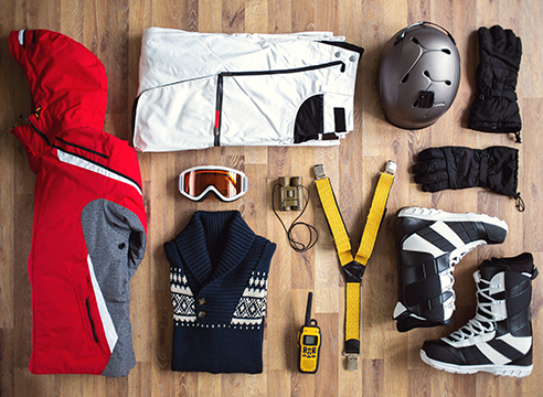 Équipement de ski et vêtements d’hiver disposés sur un sol en bois.