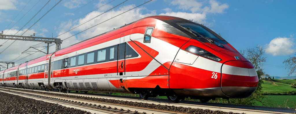 Train à grande vitesse Frecciarossa de Trenitalia roulant sur les rails en pleine campagne sous un ciel bleu partiellement nuageux.